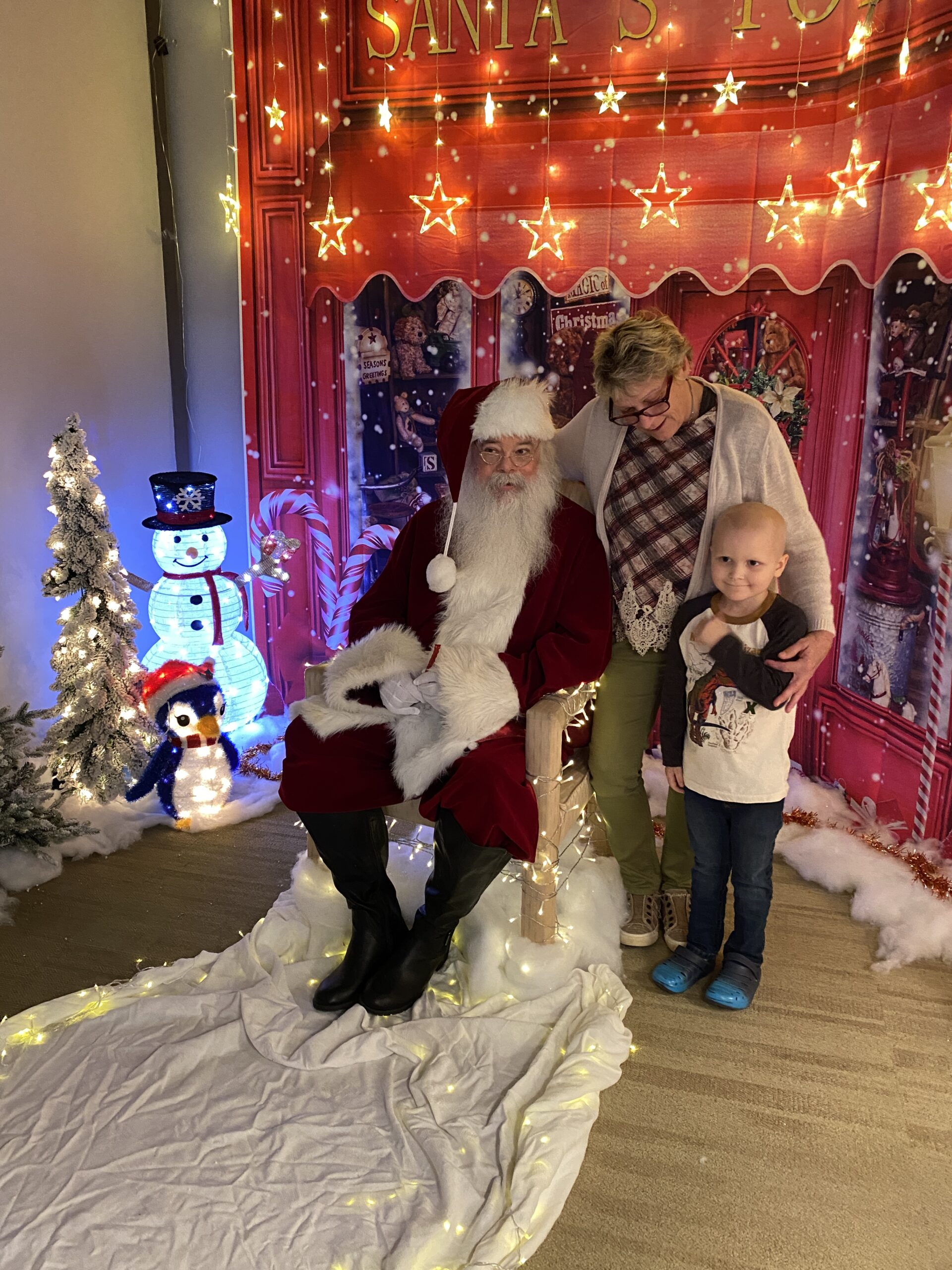 a boy and his grandmother stand next to santa