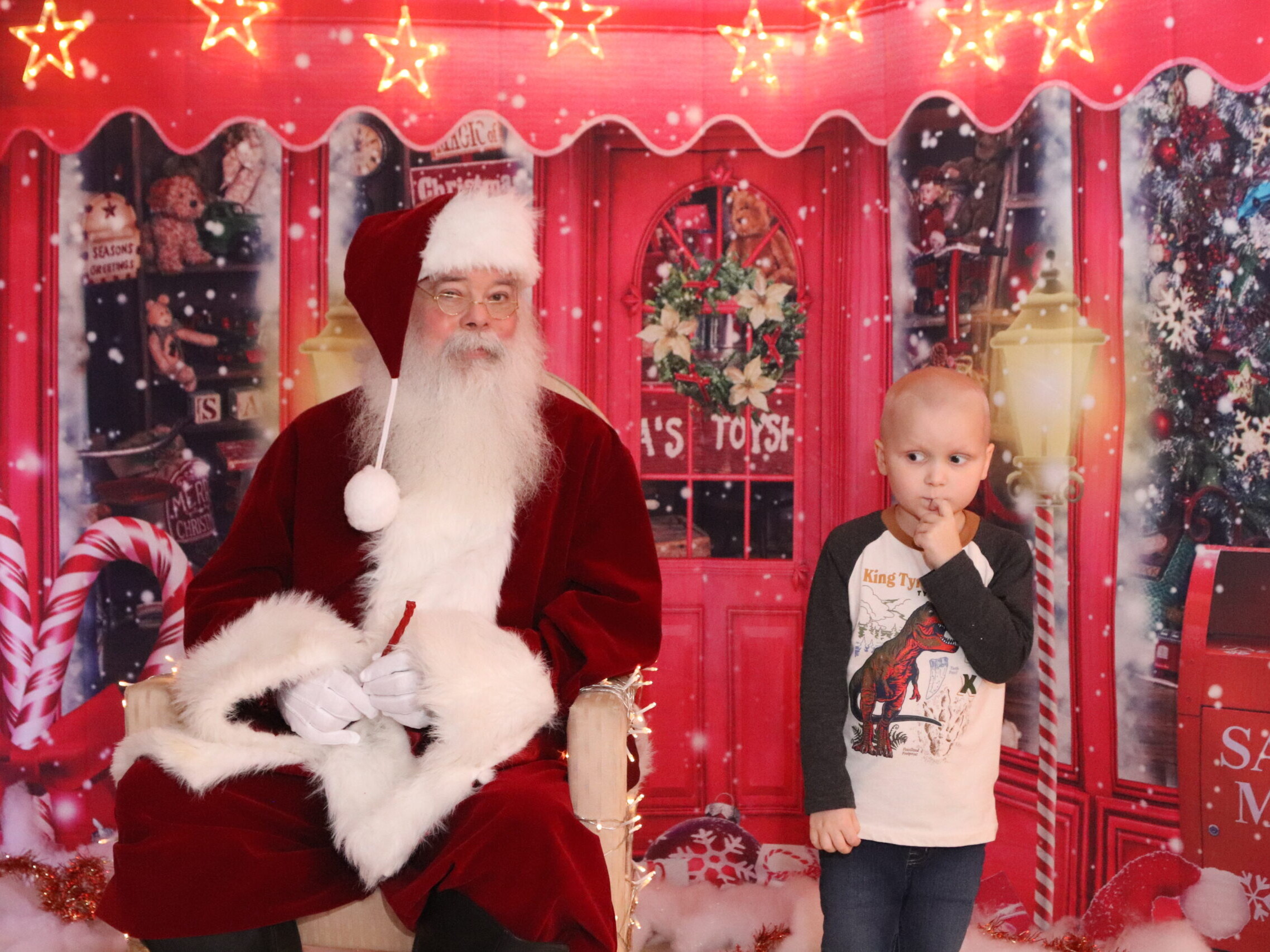 a little boy stands next to Santa