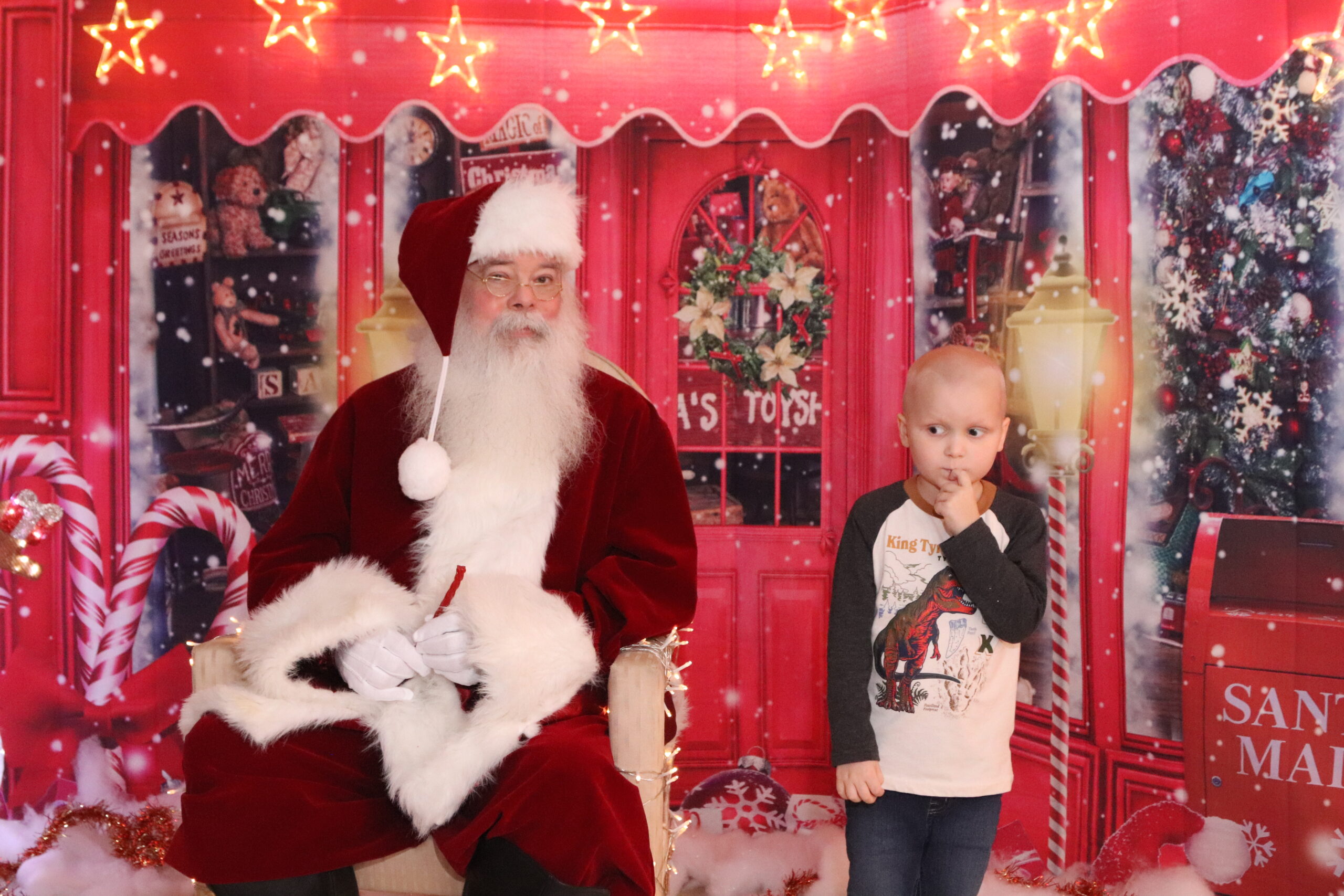 a little boy stands next to Santa