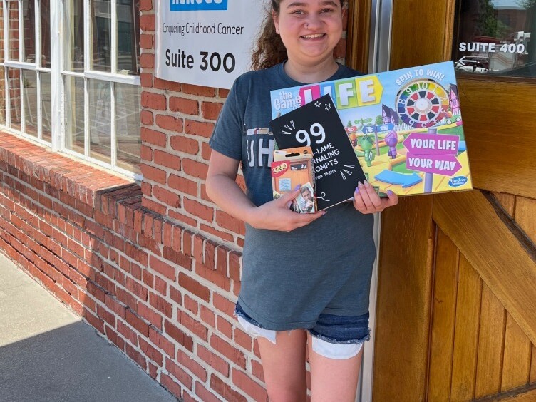 Savanna is standing outside holding up three games