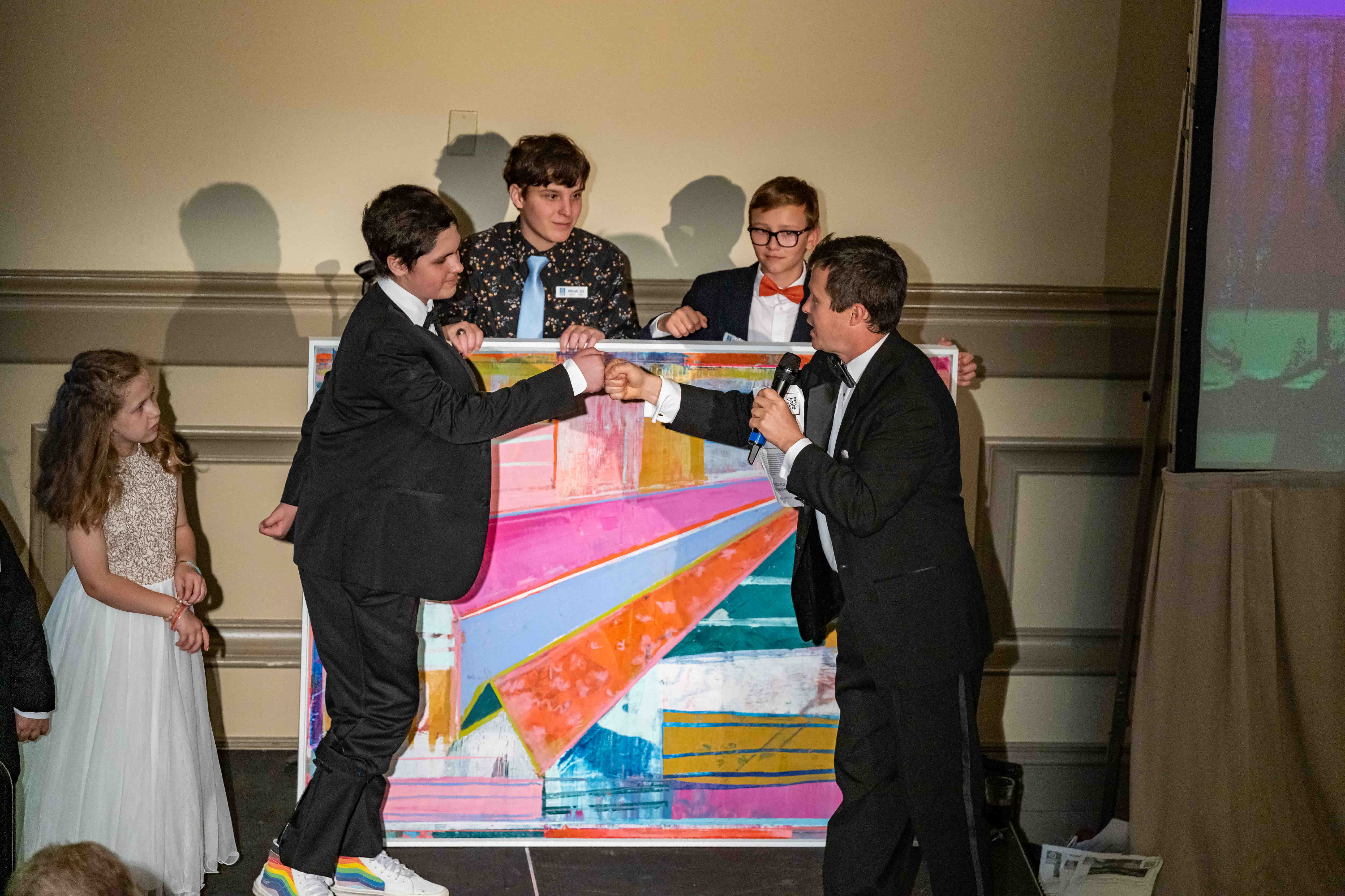 A boy fistbumps the presenter at the gala