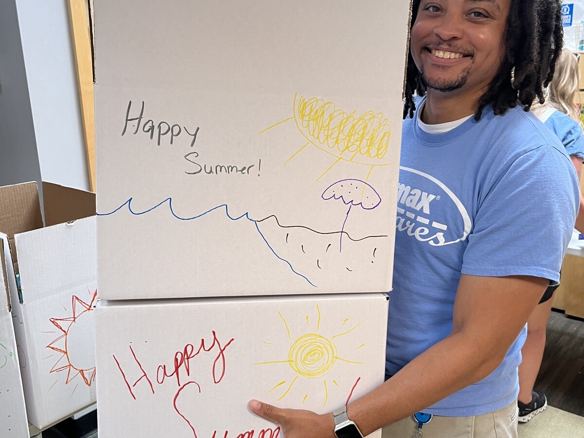 Man is carrying two boxes decorated with words Happy Summer