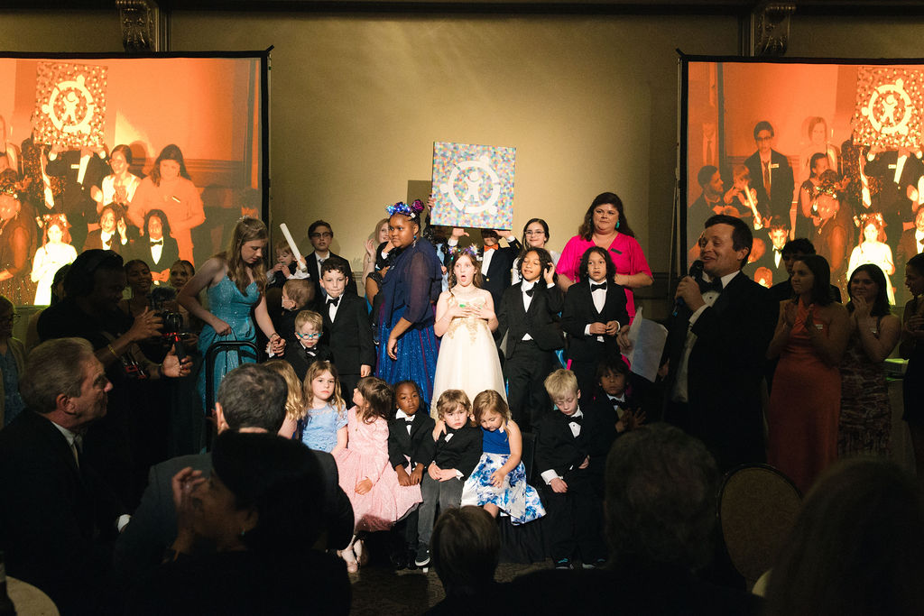 Group of kids are standing the stage with the painitng
