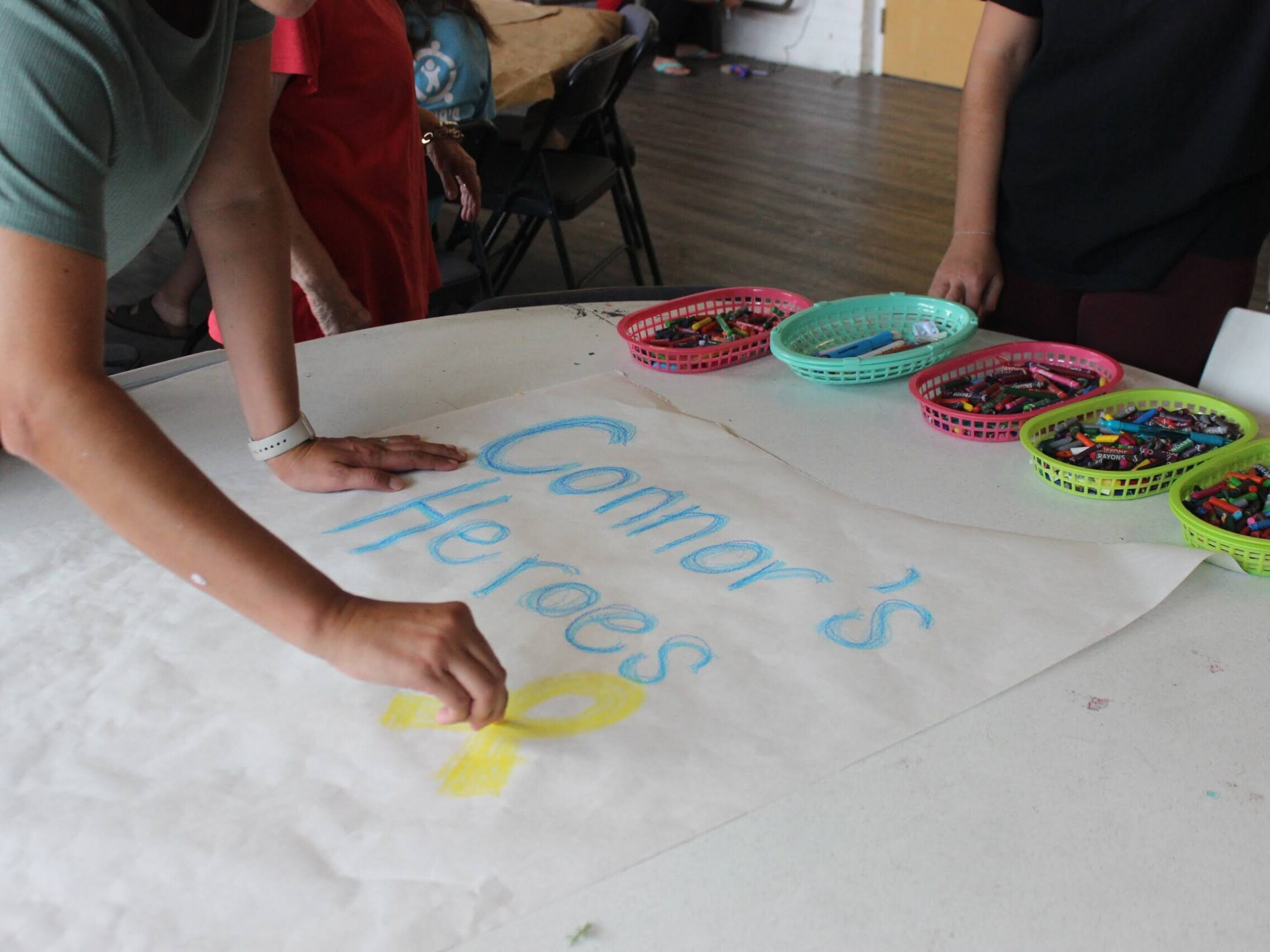 People color a sheet of paper that says Connor's Heroes