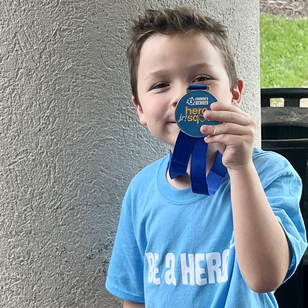A boy holds up his medal for Jr. Hero Squad
