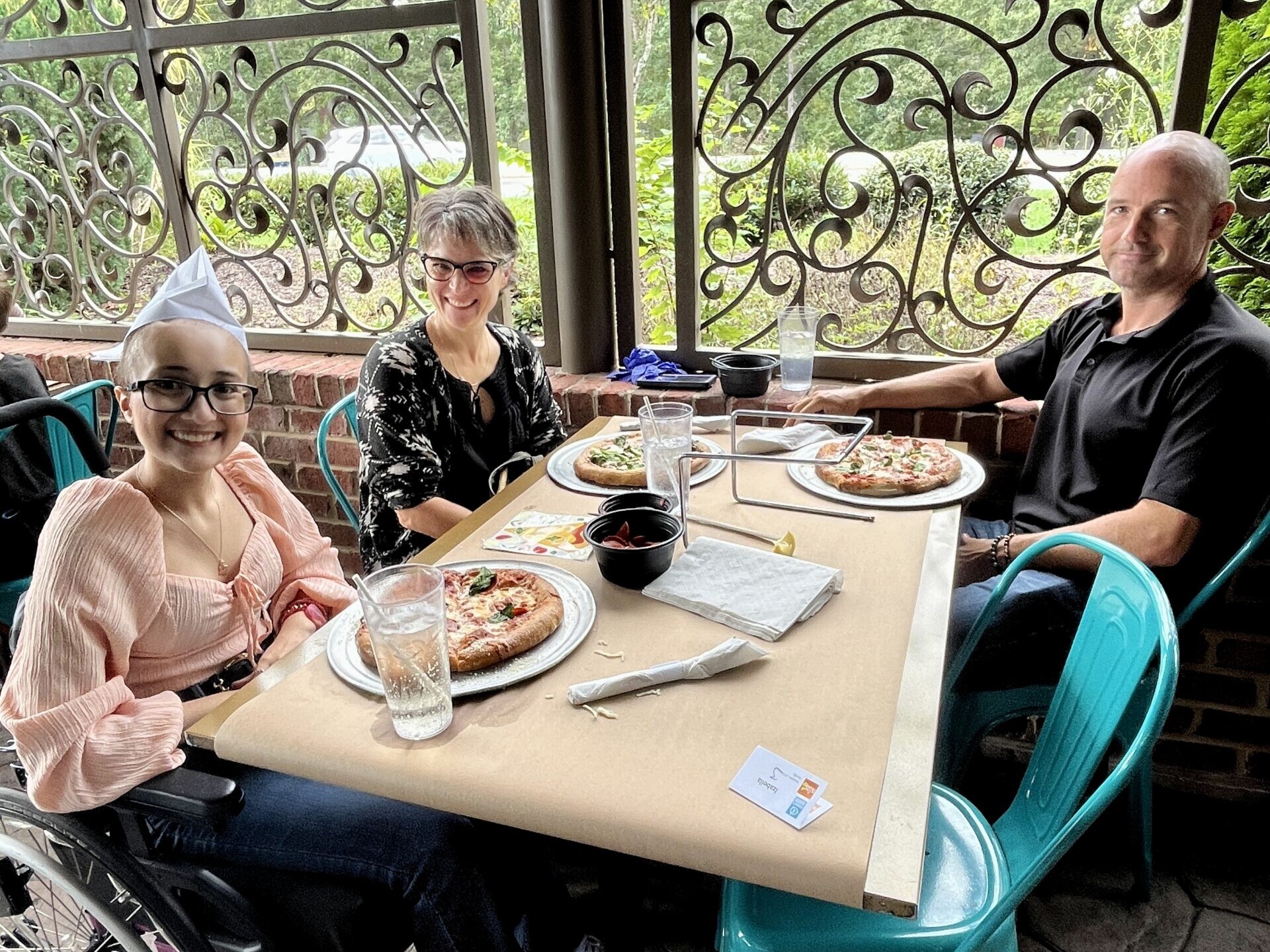 A teen is eating pizza with her parents