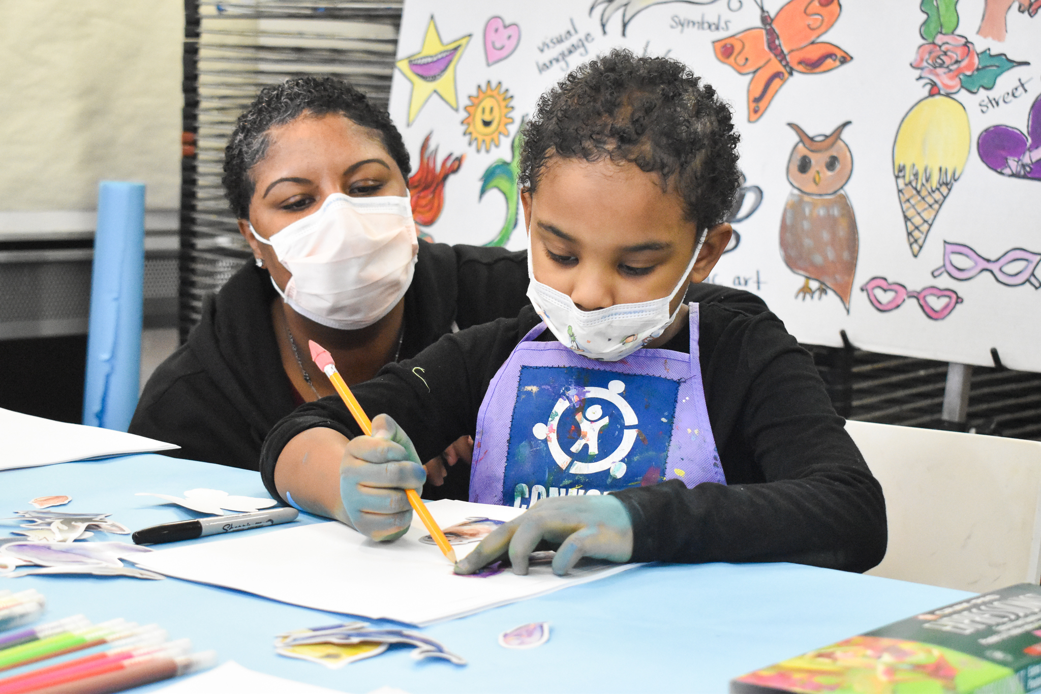 A child and. her mom work on a painting in an art studio