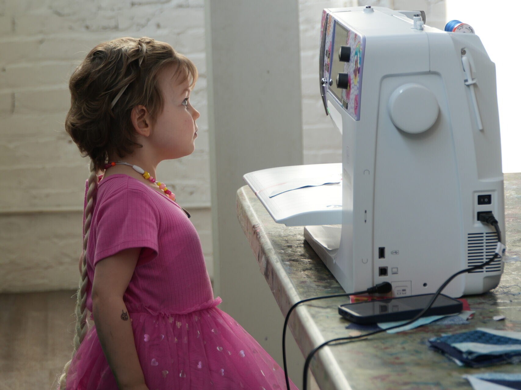 a child is sitting at a sewing machine