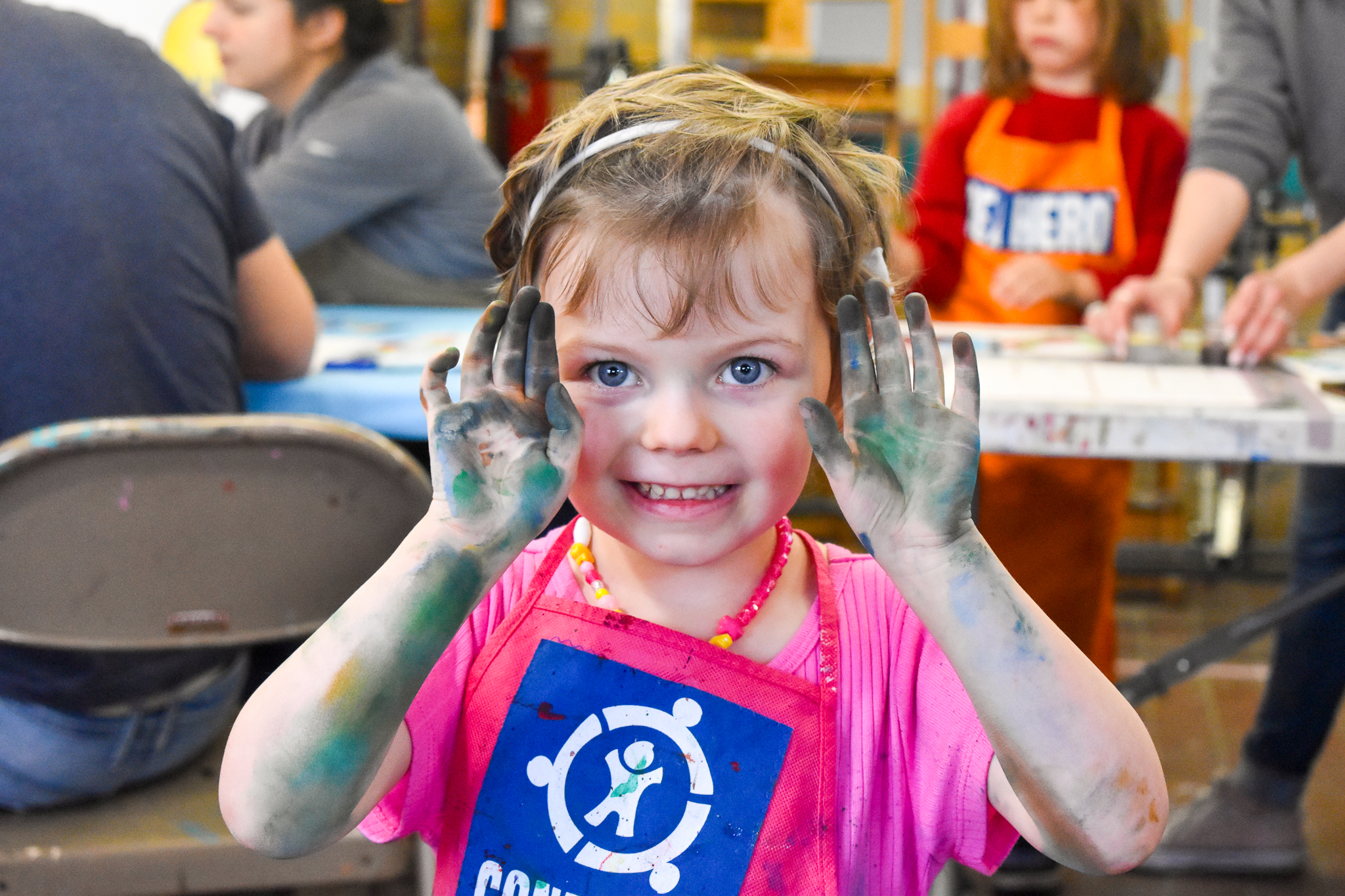 A child holds up her hands covered in paint
