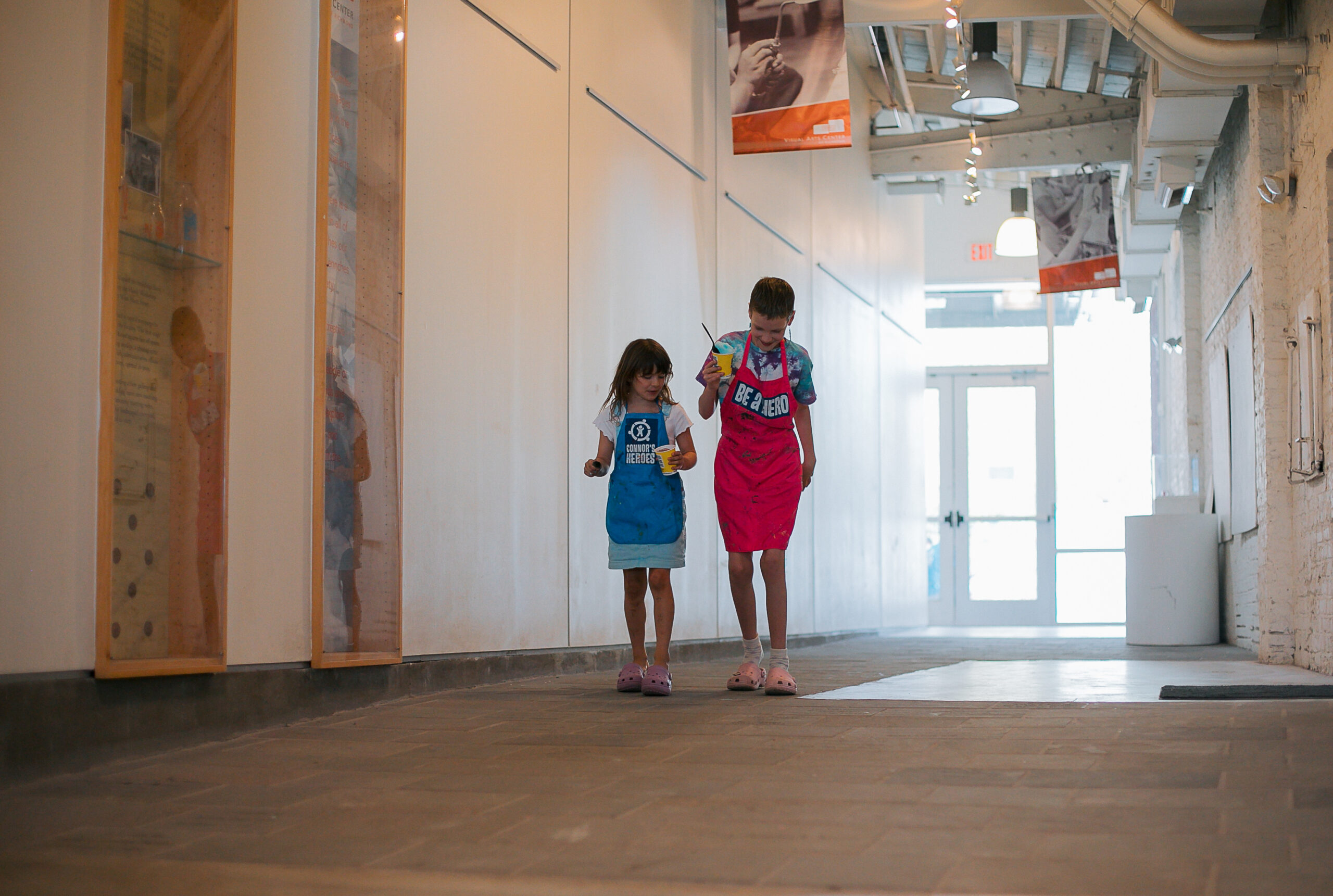 Two kids walk down a hallway