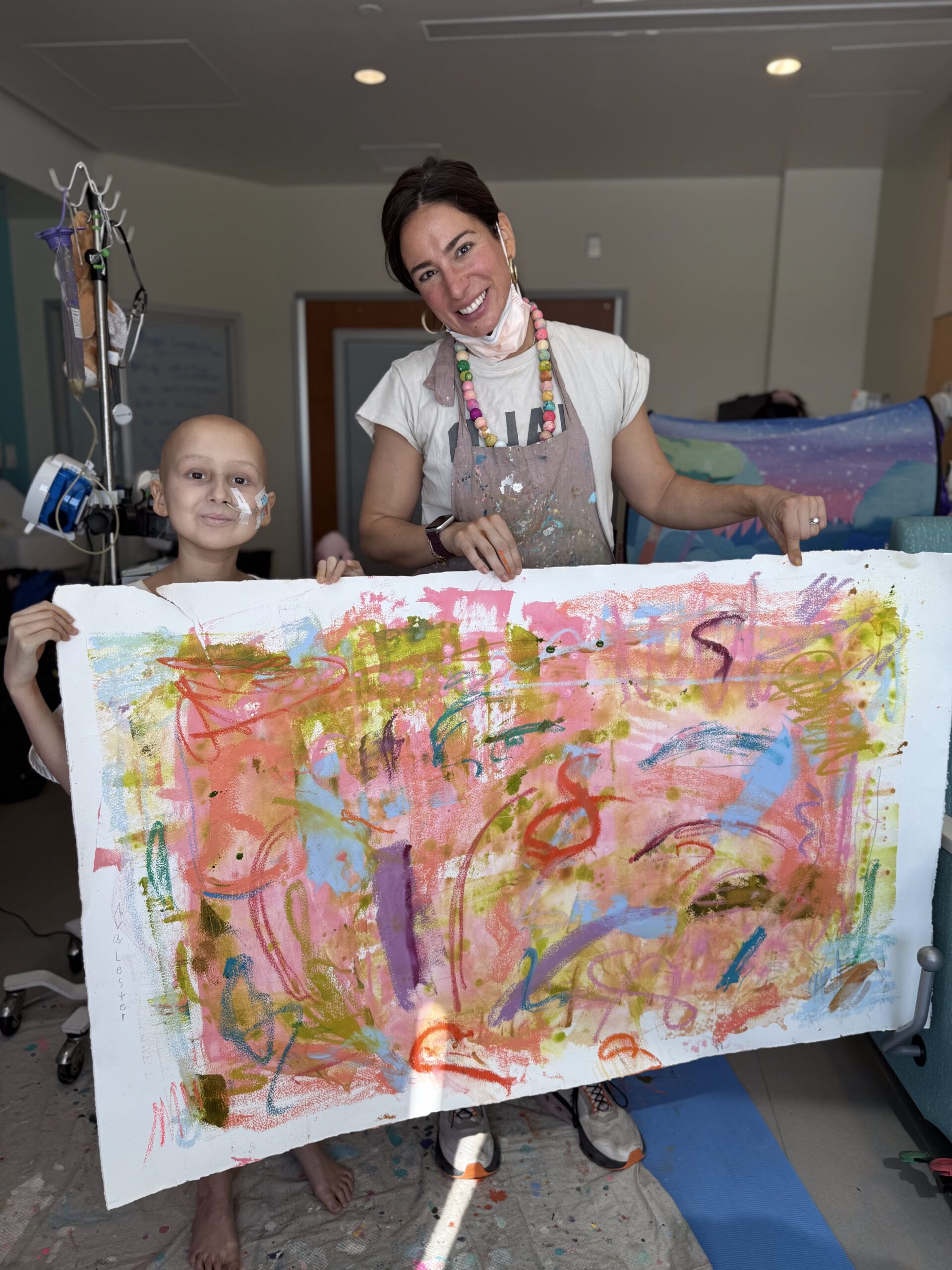 a child and an artist show off their painting