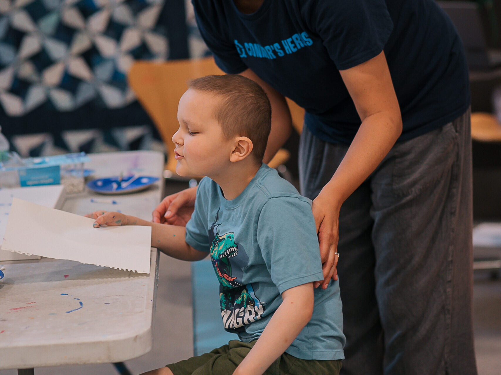 An adult is helping a boy with an art project
