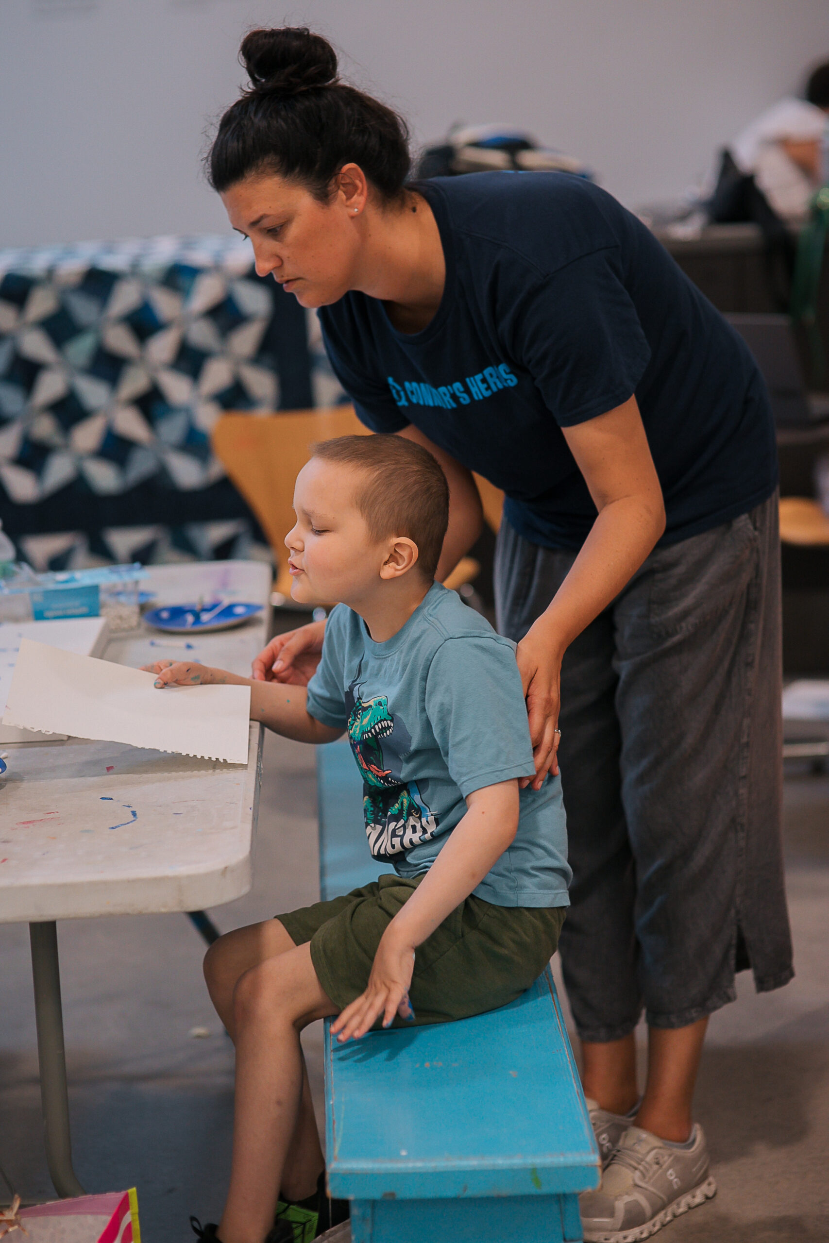 An adult is helping a boy with an art project