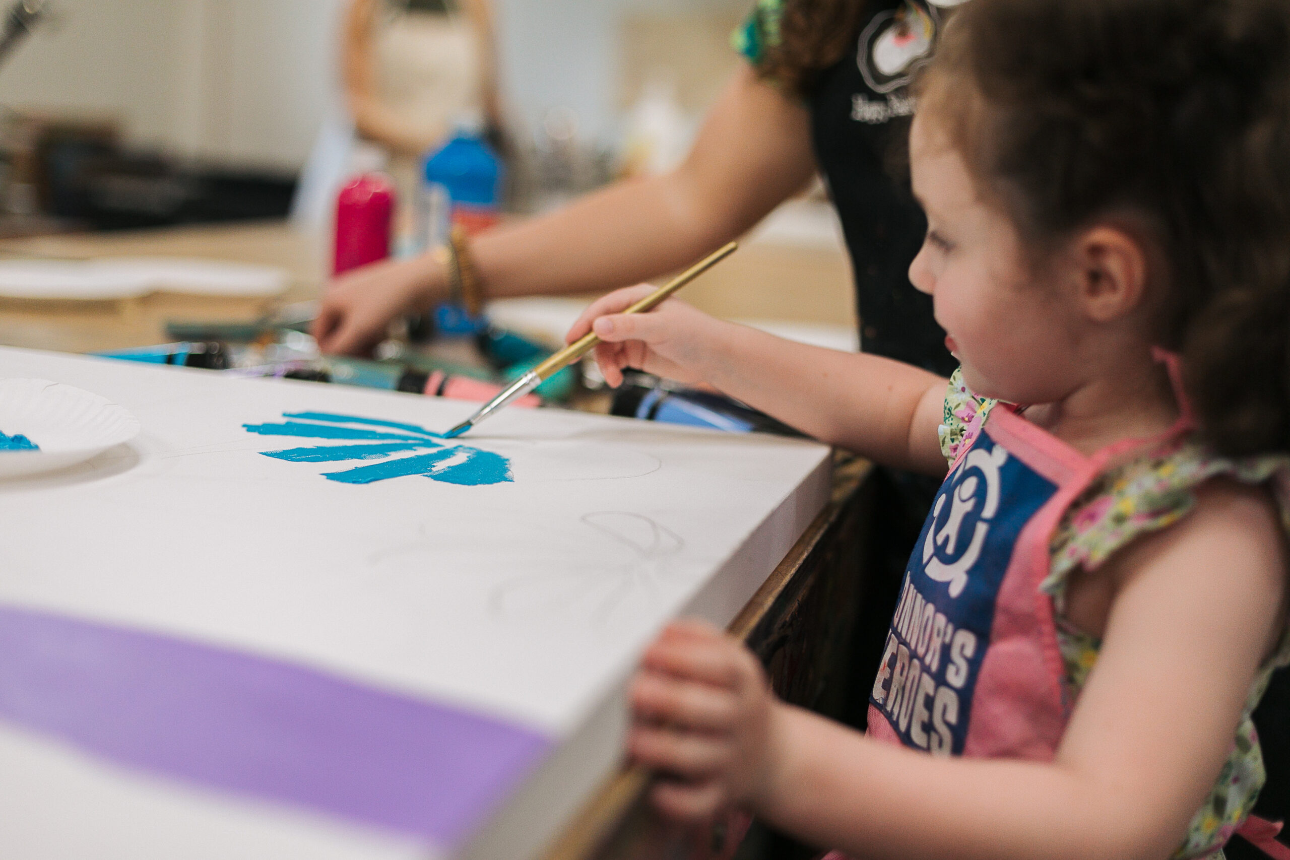 A girl paints a blue flower
