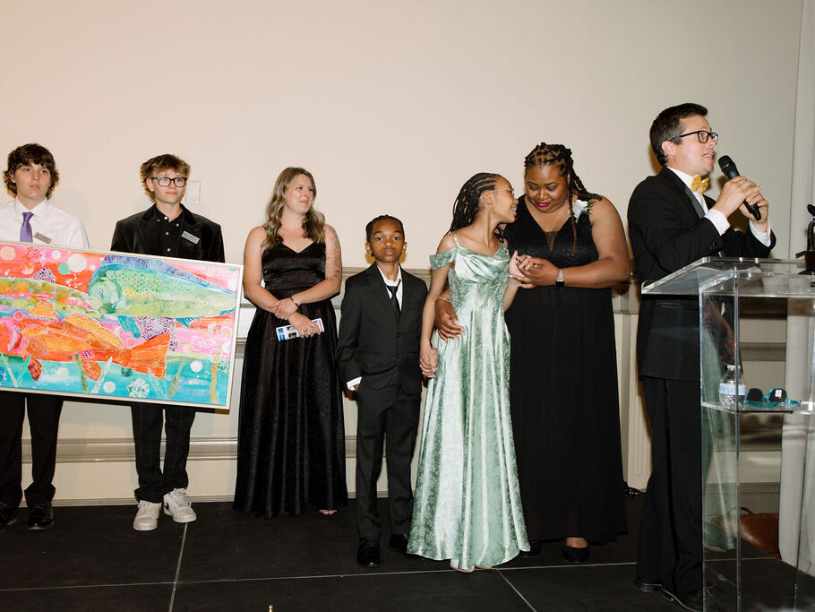 a girl and her family stand on stage at the heroes art ball