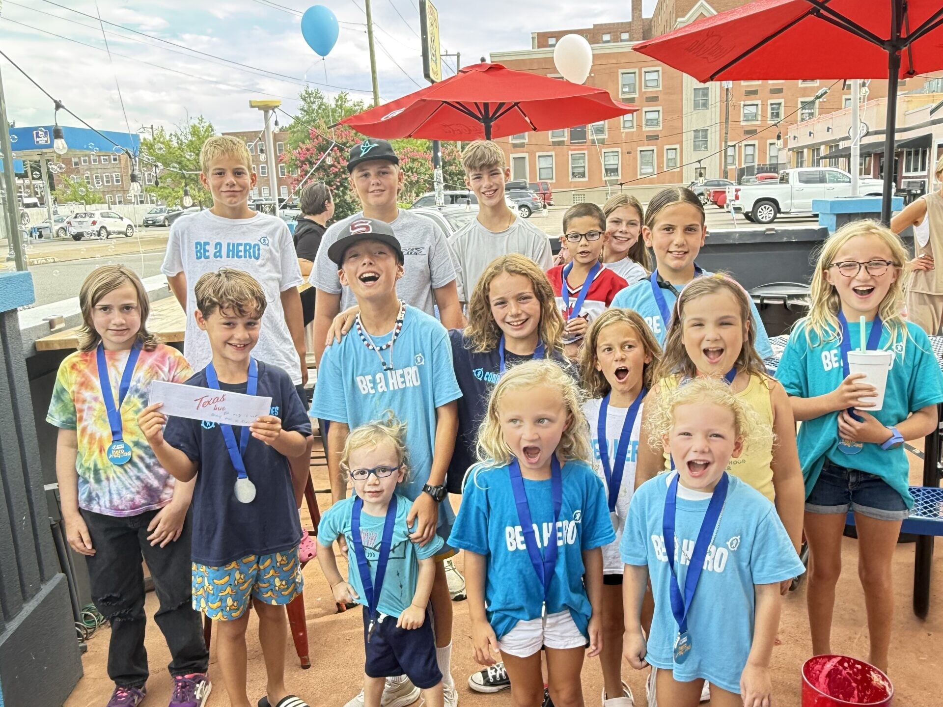 A group photo of kids wearing Be A Hero shirts