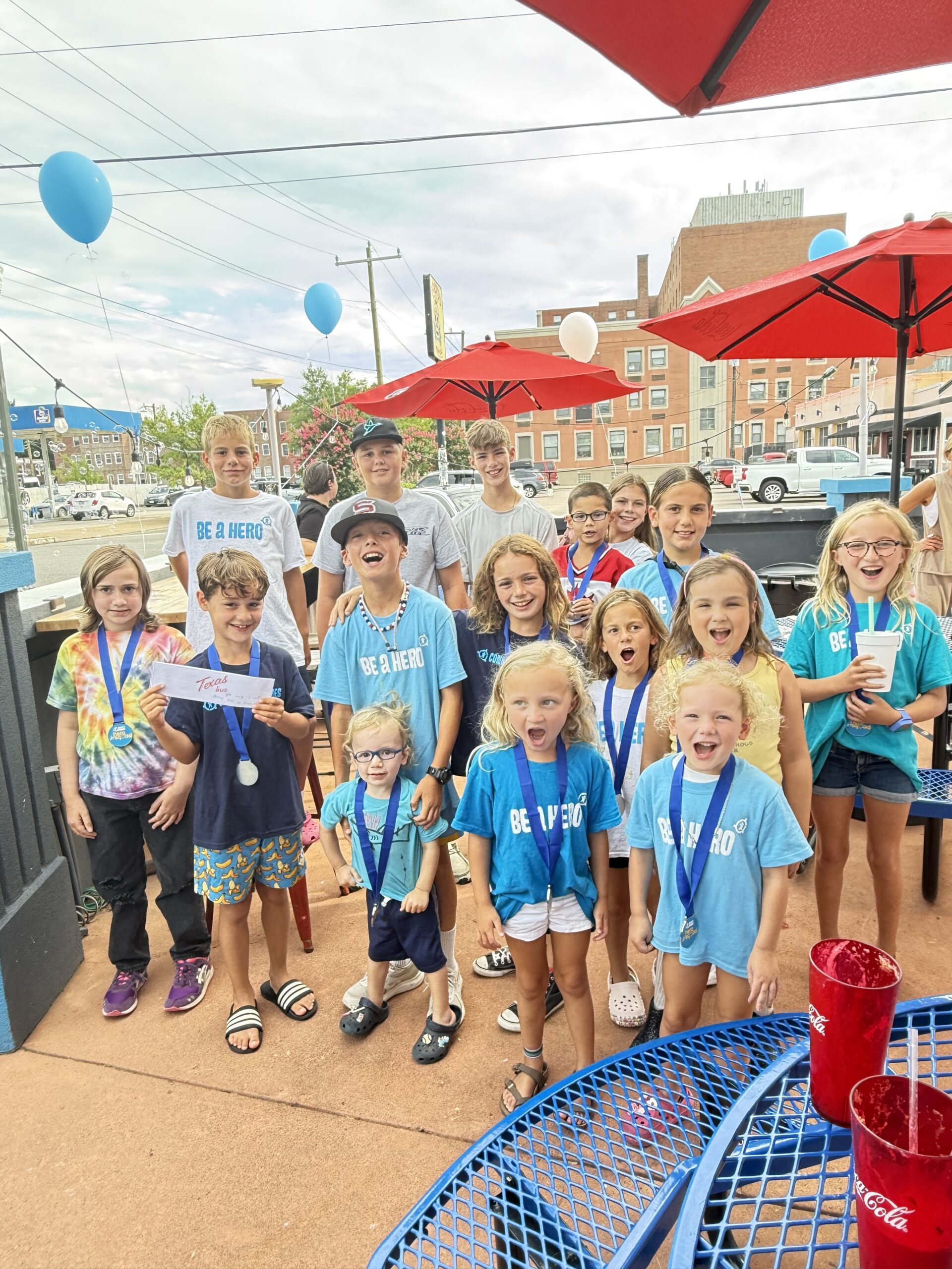 A group photo of kids wearing Be A Hero shirts