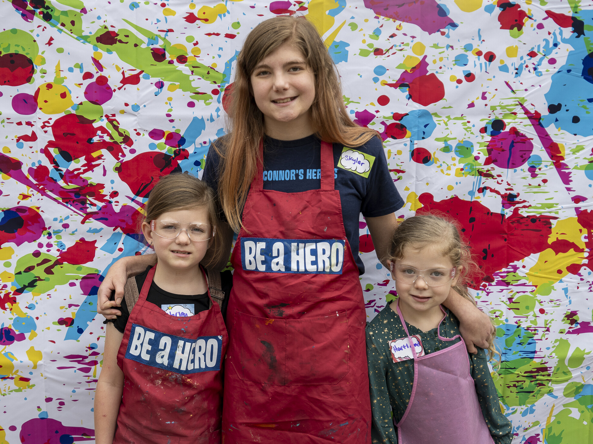 Three girls stand in front of a backdrop for a photo